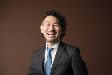 Smiling businessman in suit on brown background