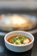 Chopped garlic and chopped green chile in sukiyaki dipping