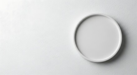 A clean, round white plate is positioned on the right side of a textured white background, offering ample copy space