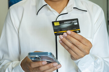 An Asian man making an online purchase via smartphone with a credit card in hand; the scene reflects mobile commerce and seamless digital payment integration. Lifestyle concept.