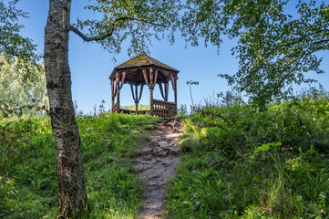 Wooden gazebo on a hill in the forest.