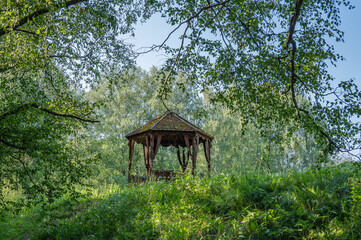 Wooden gazebo on a hill in the forest.