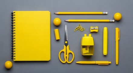 Overhead shot of a yellow-themed stationery set arranged on a gray background, including a notebook, pencils, scissors, sharpener, clips, and other office supplies.