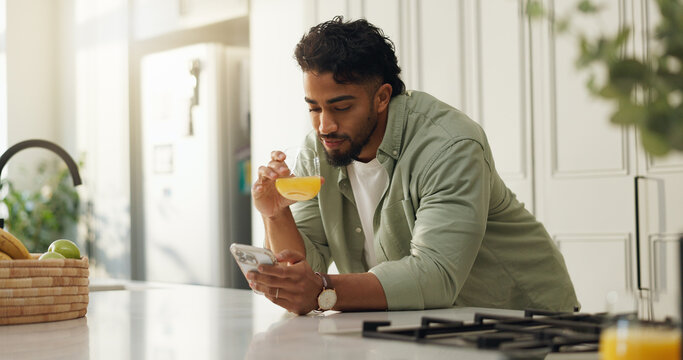 Home, orange juice and man in kitchen, smartphone and typing with social media, wellness and email. Nutrition, internet or cellphone with communication, citrus drink or message to contact or chatting