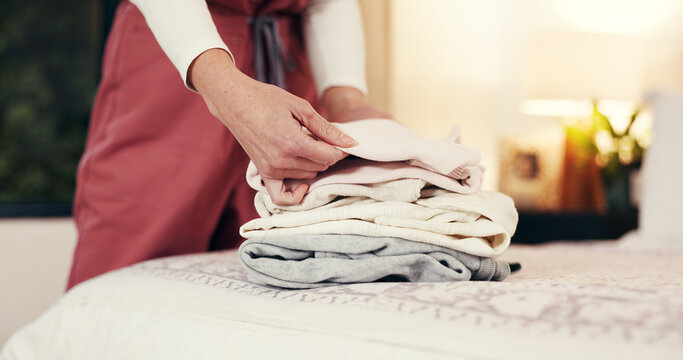 Hands folding laundry, bed and house for hygiene routine, services and nurse in bedroom. Person, caregiver and packing clean clothes with garments, fabric or assisted living career at retirement home