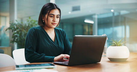 Woman, laptop and night at office with finance review, problem solving or typing with profit...