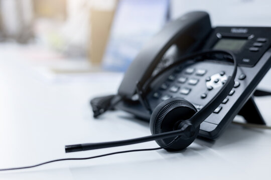 close up soft focus on headset with telephone devices at office desk for customer service support concept