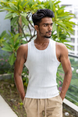 Handsome and good looking Gen Z male model with a fashionable black haircut, is posing in a trendy outfit with a gym fit muscled body
