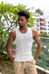 Handsome and good looking Gen Z male model with a fashionable black haircut, is posing in a trendy outfit with a gym fit muscled body