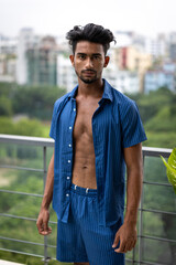 Handsome and good looking Gen Z male model with a fashionable black haircut, is posing in a trendy outfit with a gym fit muscled body