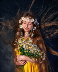 Close up portrait of young beautiful caucasian girl wearing wreath of daisies on her head and a bouquet posing on grey background. Beautiful curly hair.