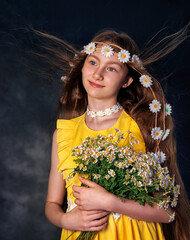 Close up portrait of young beautiful caucasian girl wearing wreath of daisies on her head and a bouquet posing on grey background. Beautiful curly hair.