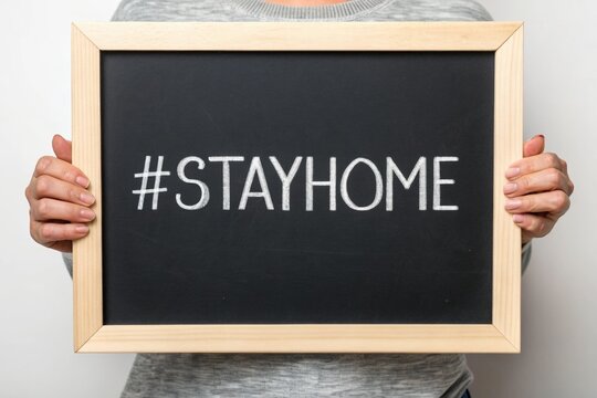 A Person Holding a Blackboard with the Message Stay Home to Promote Social Distancing and Health Awareness Campaign