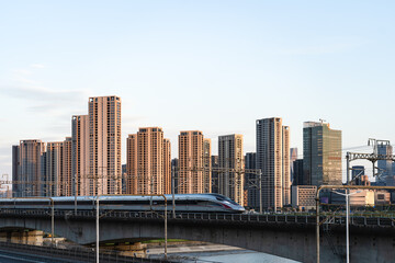 Obraz premium Under the setting sun, high-speed trains run through the modern urban area, embodying the concepts of urban speed and transportation