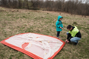 Setting up a colorful tent together in the lush, peaceful meadow during a crisp morning light...