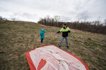 Father and child share a bonding moment while setting up a tent in a scenic meadow under an...