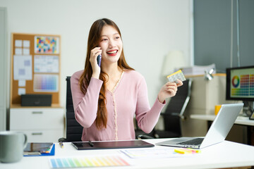 Asian designer using digital pen and laptop in a creative office, showcasing professional work,...