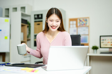 Happy creative designer works with coffee and laptop in modern office, showcasing productivity,...