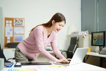 Happy creative designer works with coffee and laptop in modern office, showcasing productivity,...