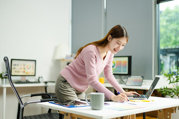 woman celebrates success while working on a tablet in a modern creative office, capturing...