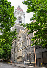 Gothic Revival First Congregational Church in downtown Portland, Oregon, showcasing its striking bell tower and intricate stone facade framed by leafy green trees