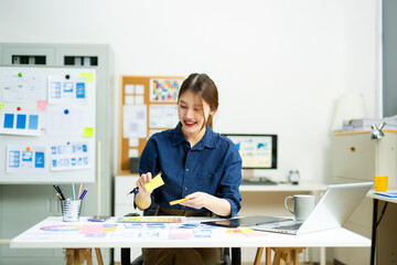 Creative designer stands at her workspace, planning UX/UI with color swatches and wireframes