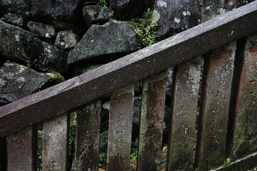 Stone wall and rustic wooden railing with moss

