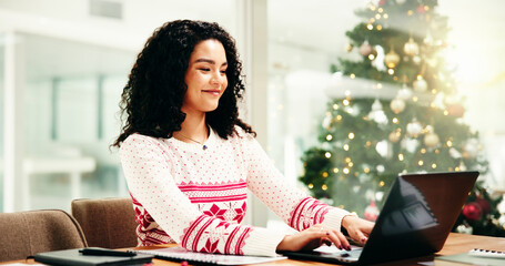 Woman, laptop and typing at Christmas, office and smile for project with festive sweater at...