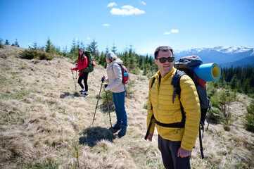 Experienced hikers walking on a mountain trail. Group of friends equipped with hiking gear climbing...