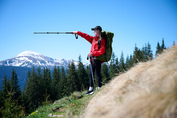 Female hiker with backpack and trekking poles walking in the mountains. Adventure lifestyle in...