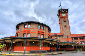 Portland's historic Union Station stands beneath a cloudy sky in Oregon, United States. Iconic Romanesque Revival structure features a rounded facade and a prominent clock tower topped with Go By