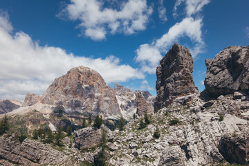 Stunning mountain range in the Dolomites under a bright blue sky filled with clouds.
