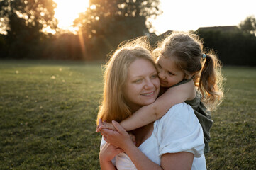 Little girl hugging her mother at sunset.