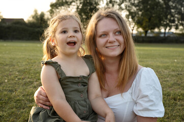 Mother and daughter smiling and looking in the same direction.