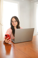 Millennial woman scrolls on smart phone working in apartment