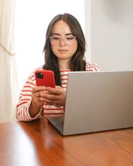 Young woman using smart phone while working from home