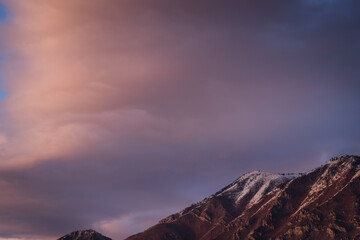 Snowy Utah mountain peak under soft pink and purple twilight clouds