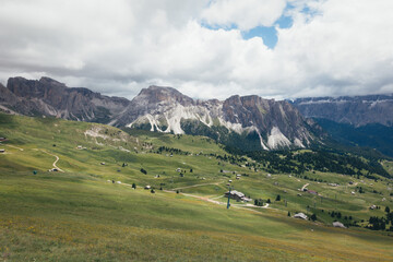 Stunning view of the Italian Dolomites with rolling green hills and dramatic mountain peaks.