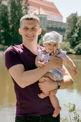 Father holding baby daughter by river outdoors