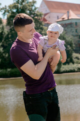 Father smiling while holding baby girl outdoors