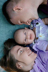 Parents lying with baby on blanket smiling
