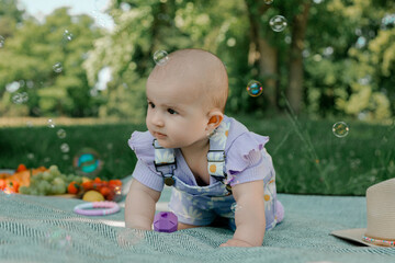 Baby girl playing on picnic blanket with bubbles