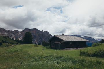 A charming wooden cabin nestled in the breathtaking Dolomites mountains on a cloudy day.