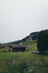 A charming chapel and cabin sit on a hillside in the breathtaking Dolomites.