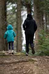 Joyful exploration on a serene forest trail during a chilly day as a young child and adult walk...
