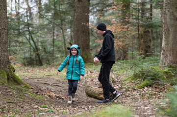 Joyful exploration through the forest as a young girl in a turquoise jacket shares laughter with a...