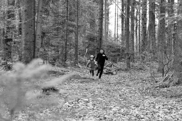 Chasing adventure among tall trees as a parent and child wander through a serene forest trail during a crisp autumn day filled with laughter and exploration