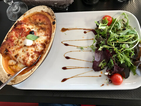 plate of lasagna bolognese accompanied by salad
