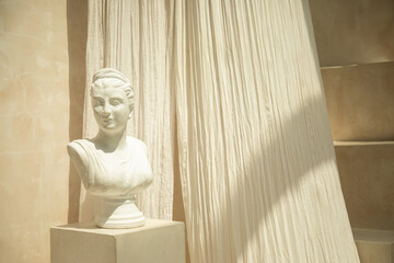 A marble bust stands elegantly in a sunlit art gallery