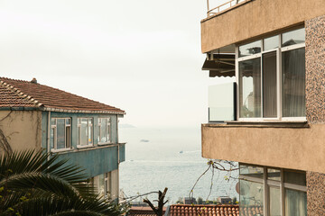 Buildings overlook a calm ocean with boats in the distance